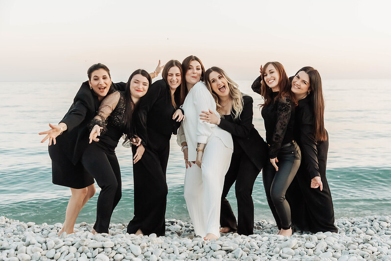 Groupe de femmes EVJF sur la plage de galets à Nice pendant une chasse au trésor, entre mer et convivialité.