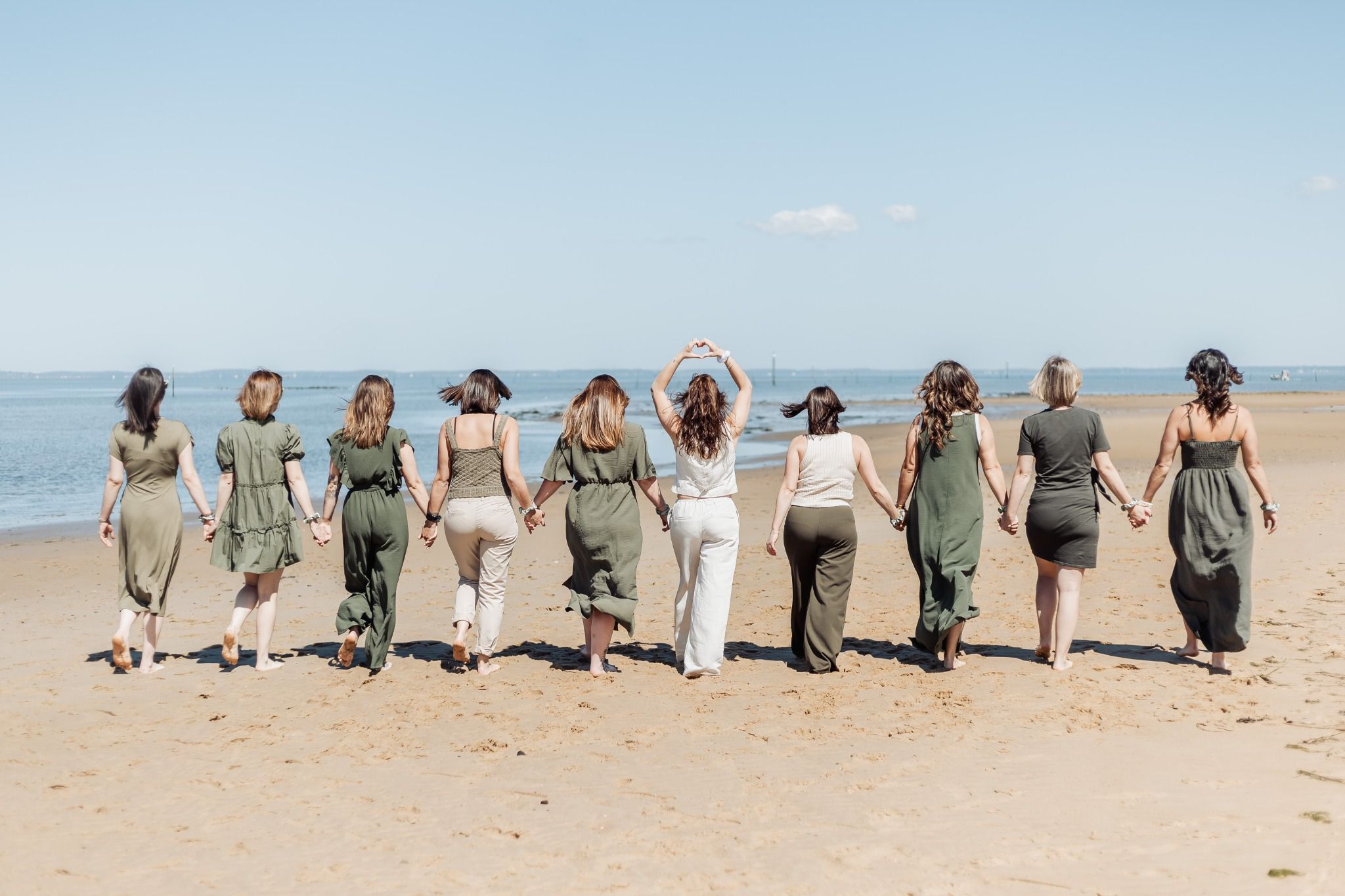 Groupe de femmes marchant main dans la main sur la plage d’Arcachon pendant un tournage de clip vidéo EVJF.