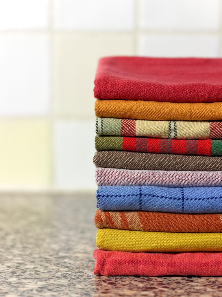 alt="Pile de tissus colorés en lin basque traditionnel, savoir-faire local découvert pendant l'EVJF"