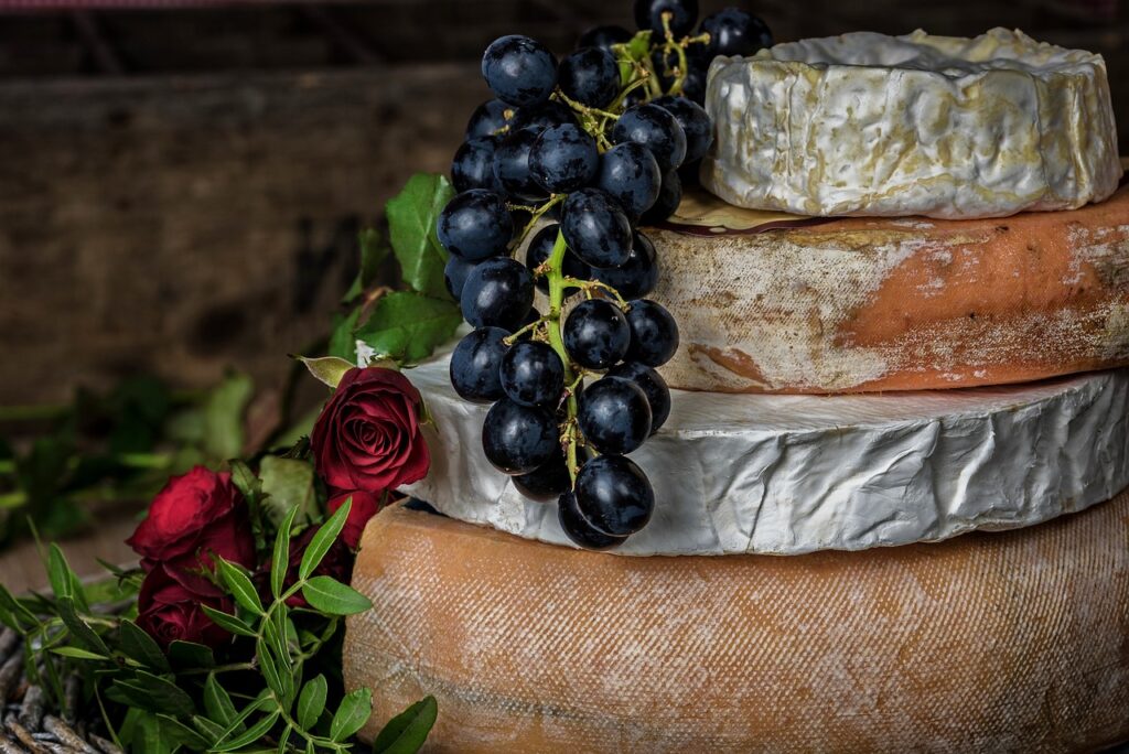 alt="Plateau de fromages affinés basques avec raisins et roses, dégustation locale à Biarritz"