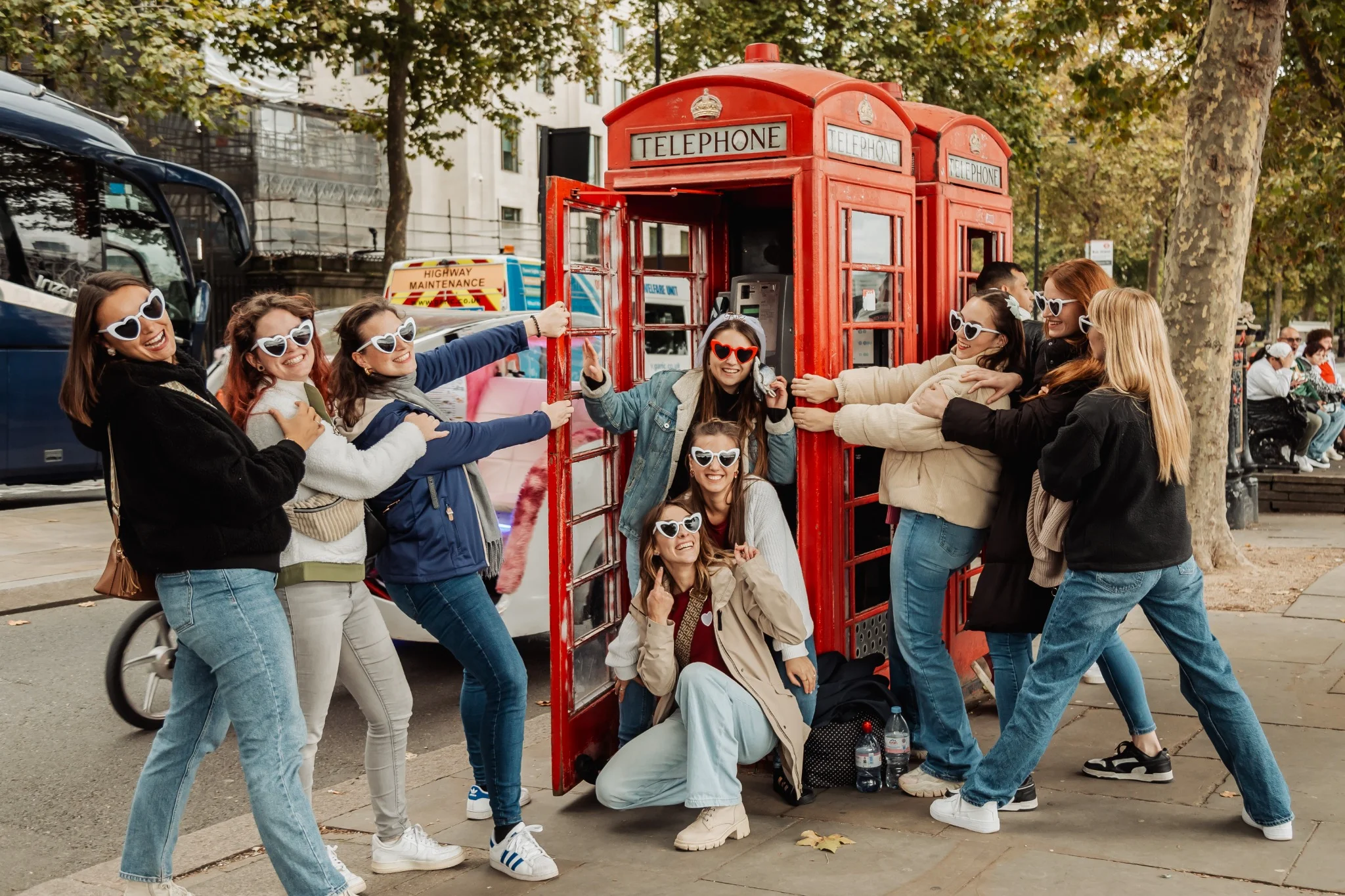 Groupe de filles lors d’un EVJF à Londres posant devant une cabine téléphonique rouge avec des lunettes en forme de cœur