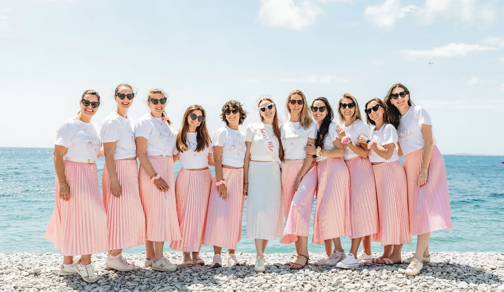 Photo de groupe EVJF à Nice avec tenues coordonnées rose sur la plage