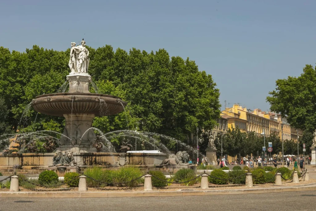 Vue de la Fontaine de la Rotonde entourée d'arbres et de bâtiments à Aix-en-Provence, un lieu iconique pour organiser un EVJF.