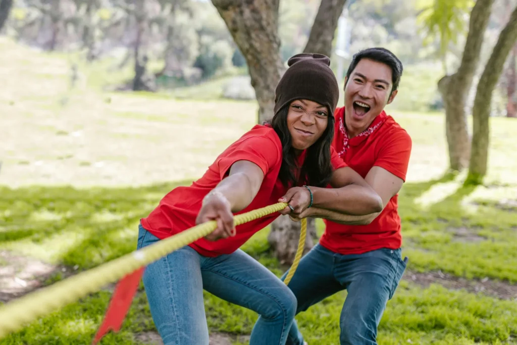 Deux participants à un EVJF s'affrontant lors d'un jeu de tir à la corde en plein air.
