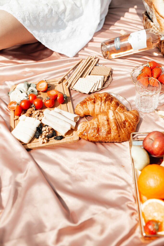 Brunch EVJF livré à Arcachon : plateau sucré-salé posé sur une serviette de plage, avec boissons fraîches et douceurs face au bassin.