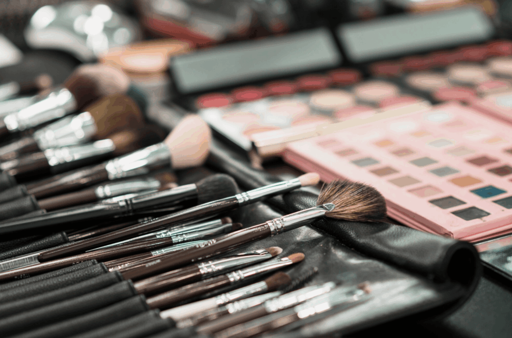 Table de maquillage installée pour une activité EVJF à Bruxelles, avec la future mariée en cours de mise en beauté et les participantes recevant des conseils