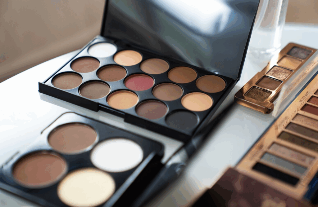 Vue d’une table joliment organisée avec palettes, pinceaux, rouges à lèvres et autres produits de maquillage lors d’un atelier beauté EVJF à Toulouse.
