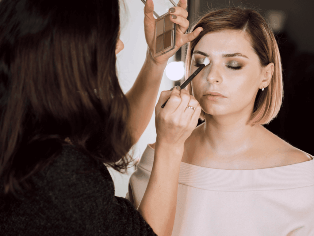 Maquilleuse professionnelle donnant des conseils à un groupe de filles lors d’un EVJF à Strasbourg, pendant la mise en beauté de la future mariée.