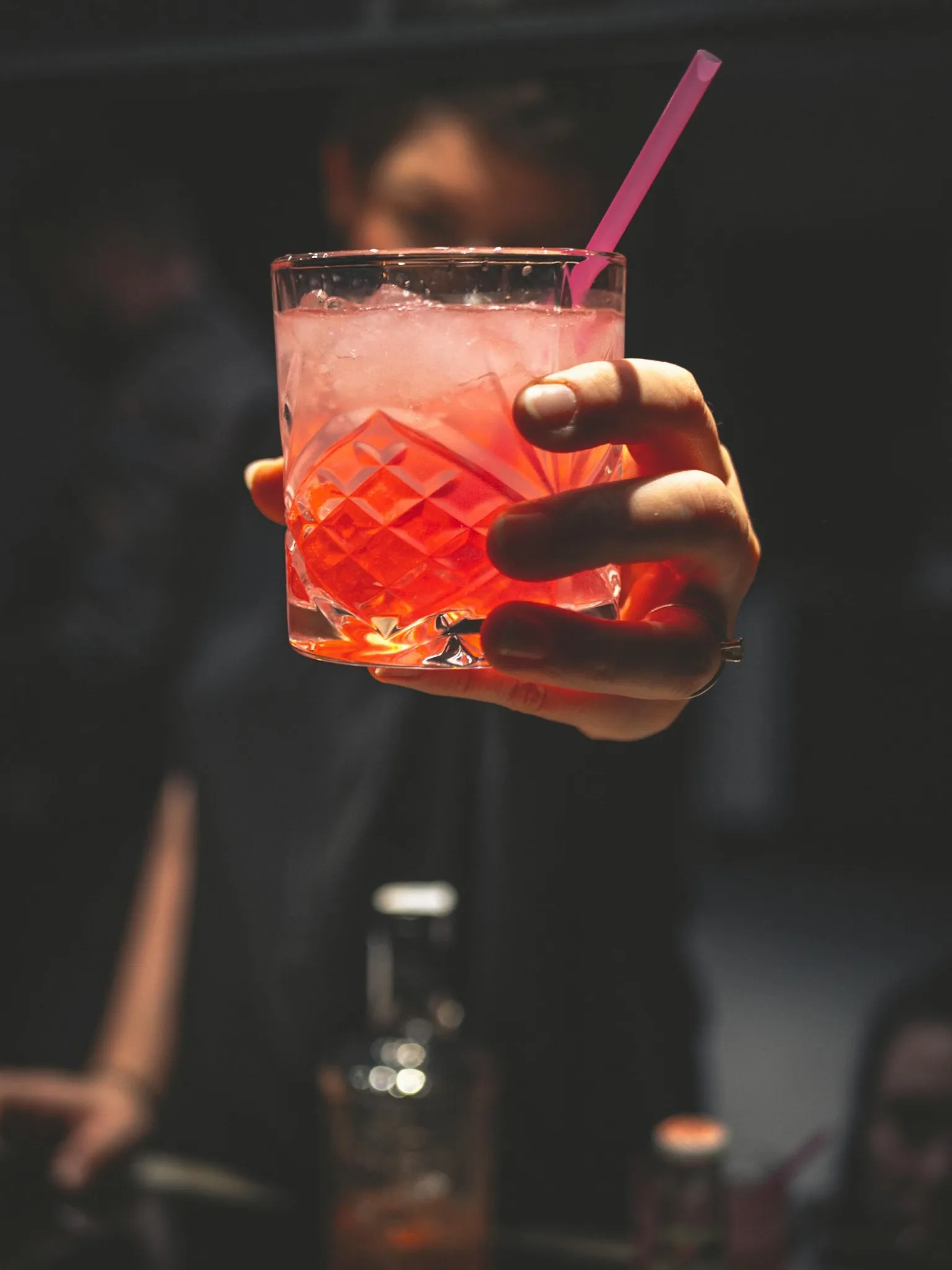 Verre de cocktail rose tendu par une participante l