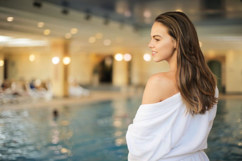 Jeune femme en peignoir appréciant l’ambiance d’un spa avec piscine intérieure lors d'un EVJF à Biarritz