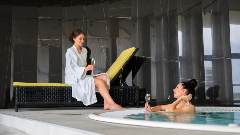 Femme en peignoir blanc dégustant une coupe de champagne près d’un jacuzzi lors d’un EVJF à BIarritz