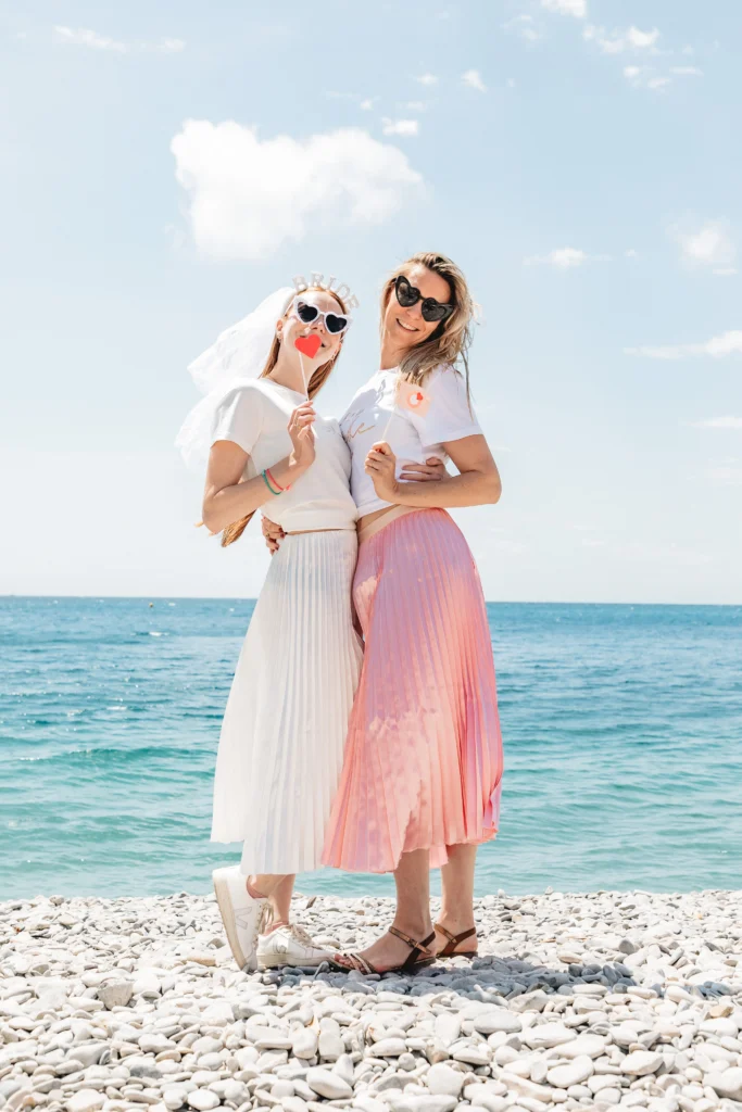 Photo EVJF fun avec la future mariée et sa témoin en bord de mer, accessoires ludiques et look coordonné