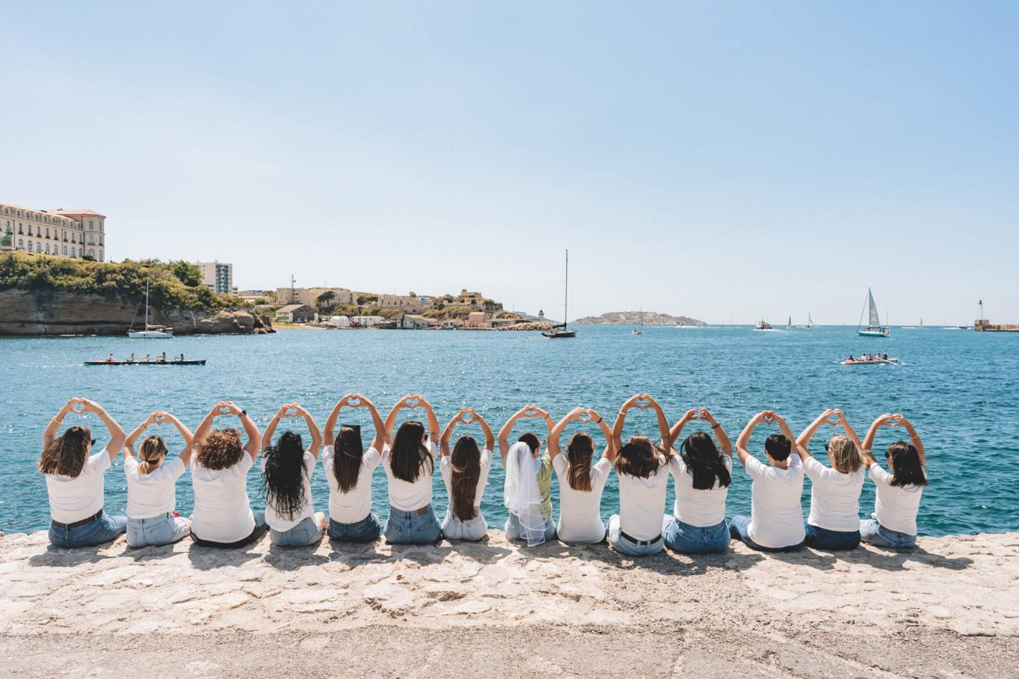 Groupe de femmes assises de dos, regardant la mer lors d’un shooting photo EVJF à Marseille.