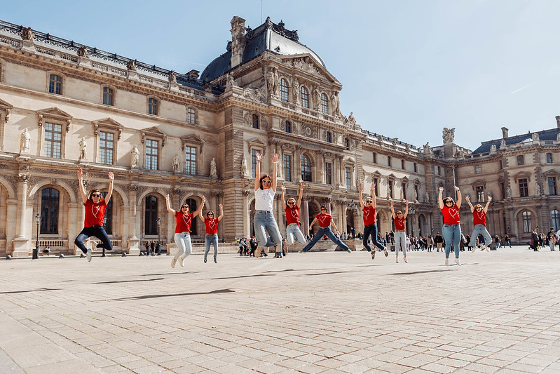 Groupe d’amies EVJF sautant joyeusement devant le Palais du Louvre sous un soleil radieux à Paris