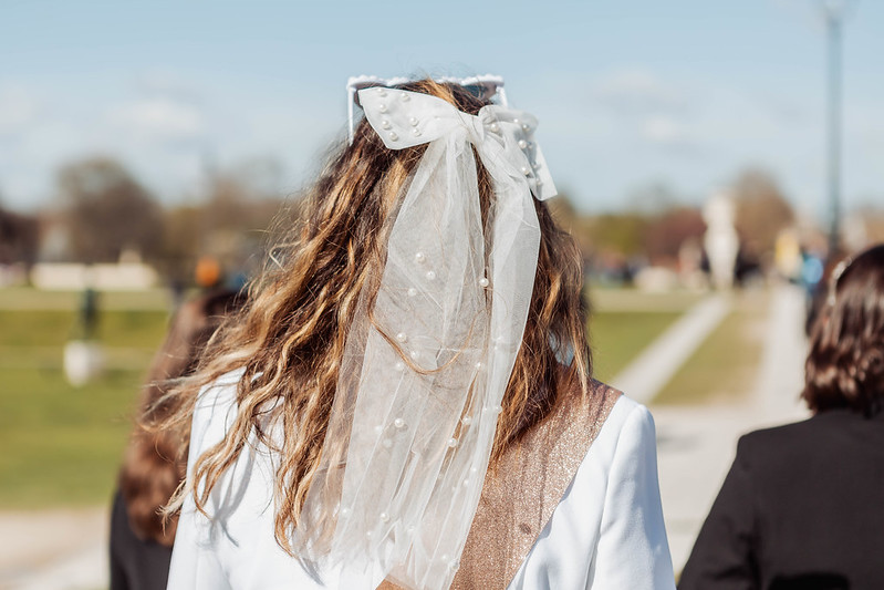 Cheveux de la future mariée avec un nœud blanc et un petit voile, dans le jardin des Tuileries à Paris, détail élégant d’un shooting EVJF