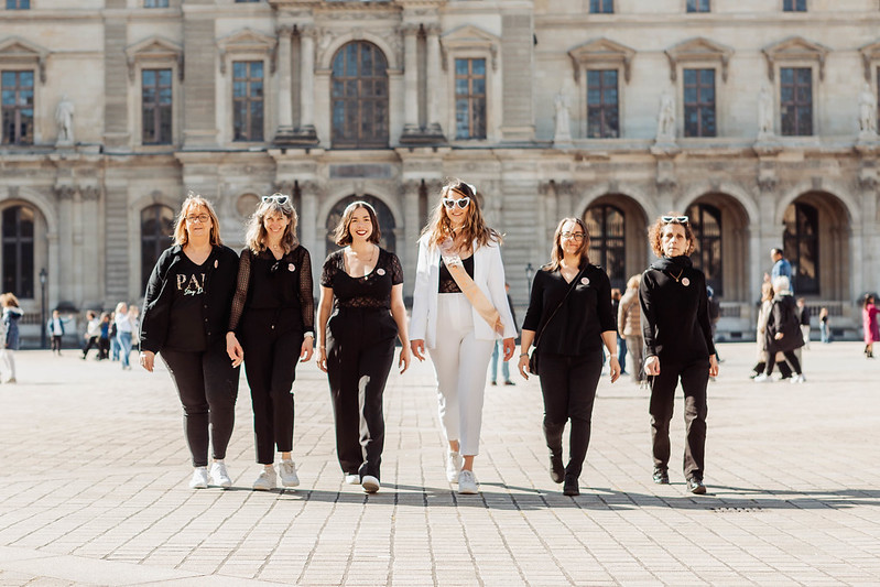 Groupe d’amies EVJF marchant devant le Palais du Louvre à Paris, tenues coordonnées, ambiance élégante et festive