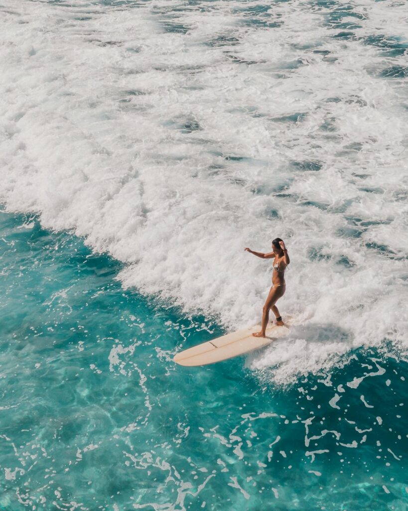 Jeune femme surfant une vague turquoise pendant une initiation pour EVJF à Biarritz