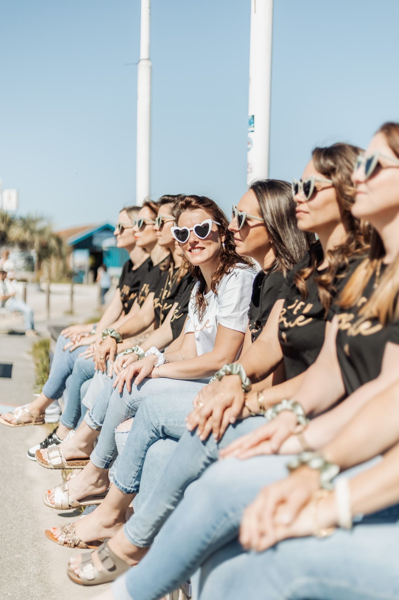 Groupe de femmes en tenue coordonnée, assises au soleil à Arcachon, prêtes pour le tournage d’un clip vidéo EVJF.