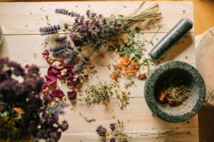 Fleurs séchées, pétales colorés et feuillages disposés sur une table en bois, prêts à être utilisés pour un atelier de création de broches florales lors d’un EVJF à Deauville.