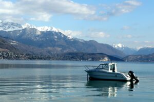 Bateau sur le lac d’Annecy, avec les montagnes enneigées en arrière-plan sous un ciel bleu.