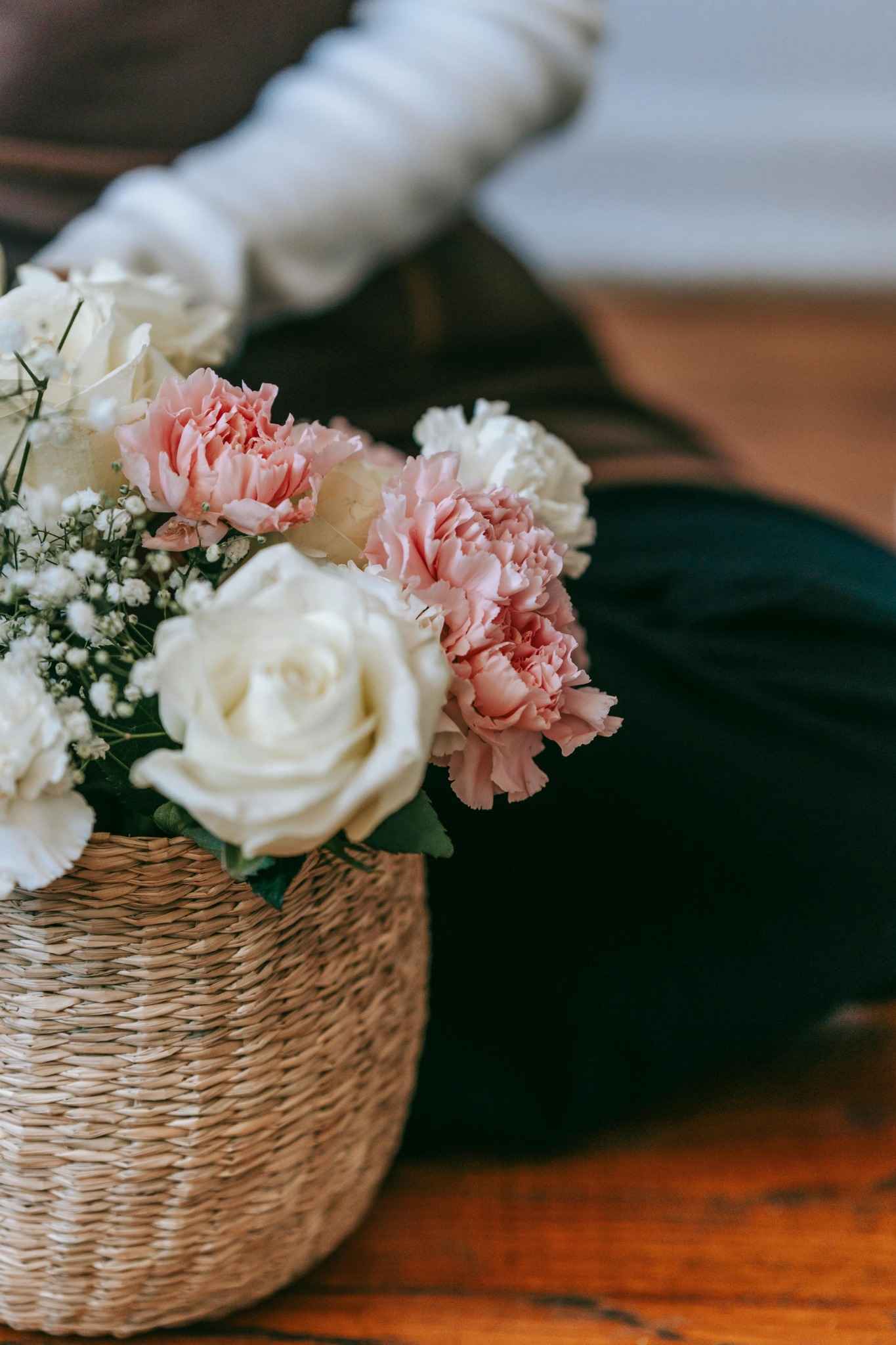 Un panier tressé rempli de fleurs fraîches blanches et roses, posé au sol à côté d’une participante.