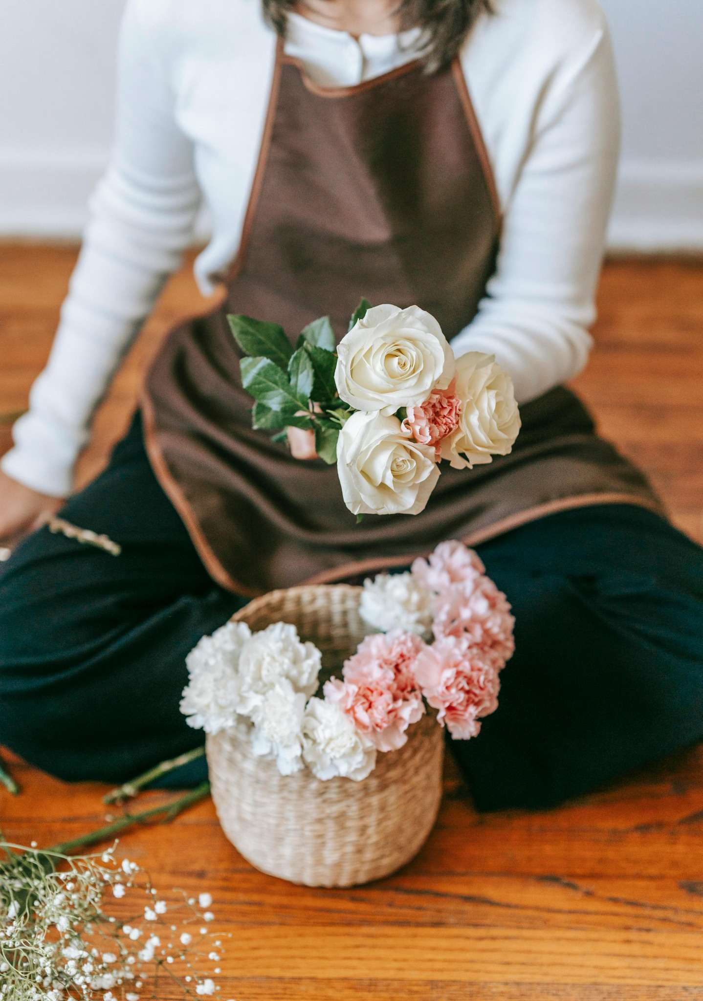 Atelier EVJF à Annecy : femme tenant un bouquet de fleurs blanches et roses, prête à créer une couronne florale.