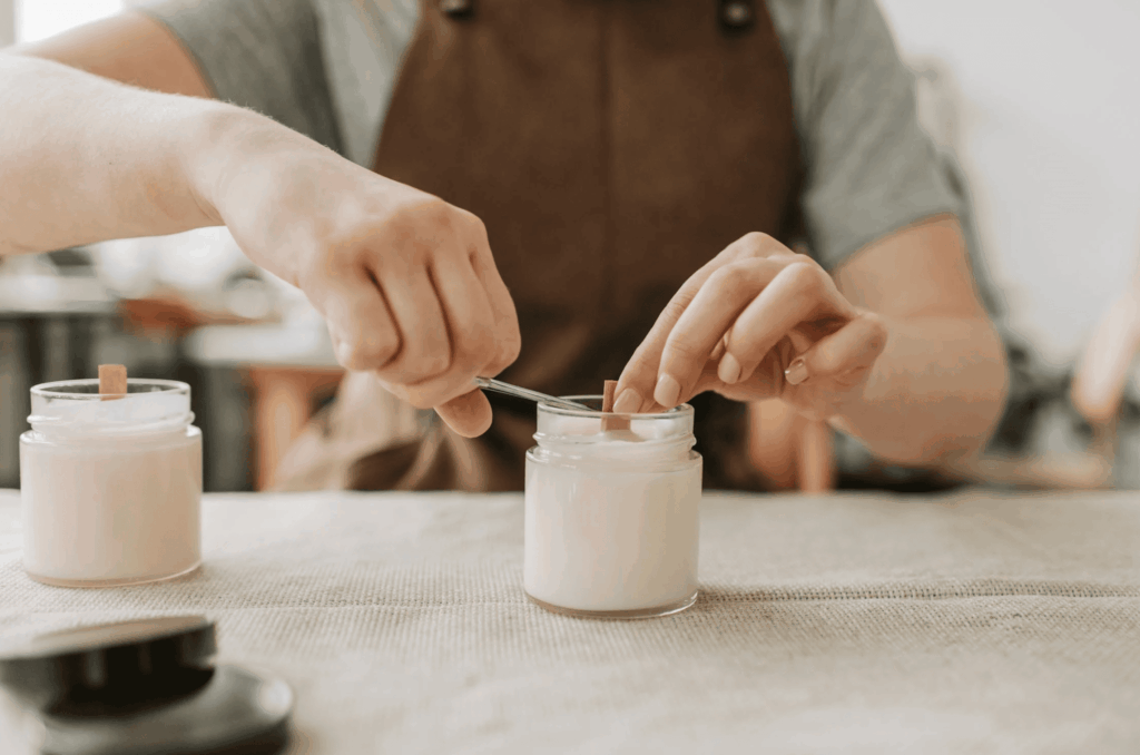 Femme décorant une bougie avec des fleurs séchées pendant un atelier EVJF à Bruxelles, moment créatif et apaisant