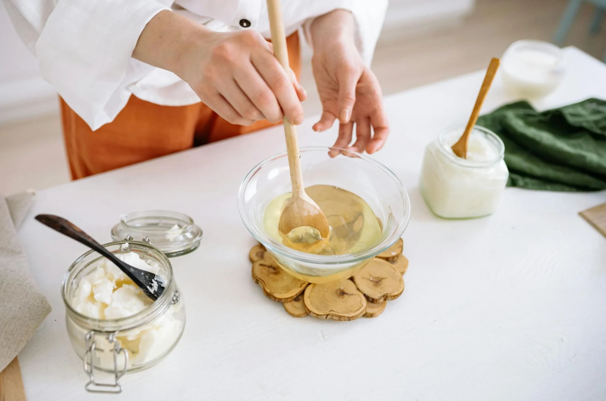 Gros plan sur les mains mélangeant de la cire fondue dans un bol en verre lors d’un atelier bougie à Lyon