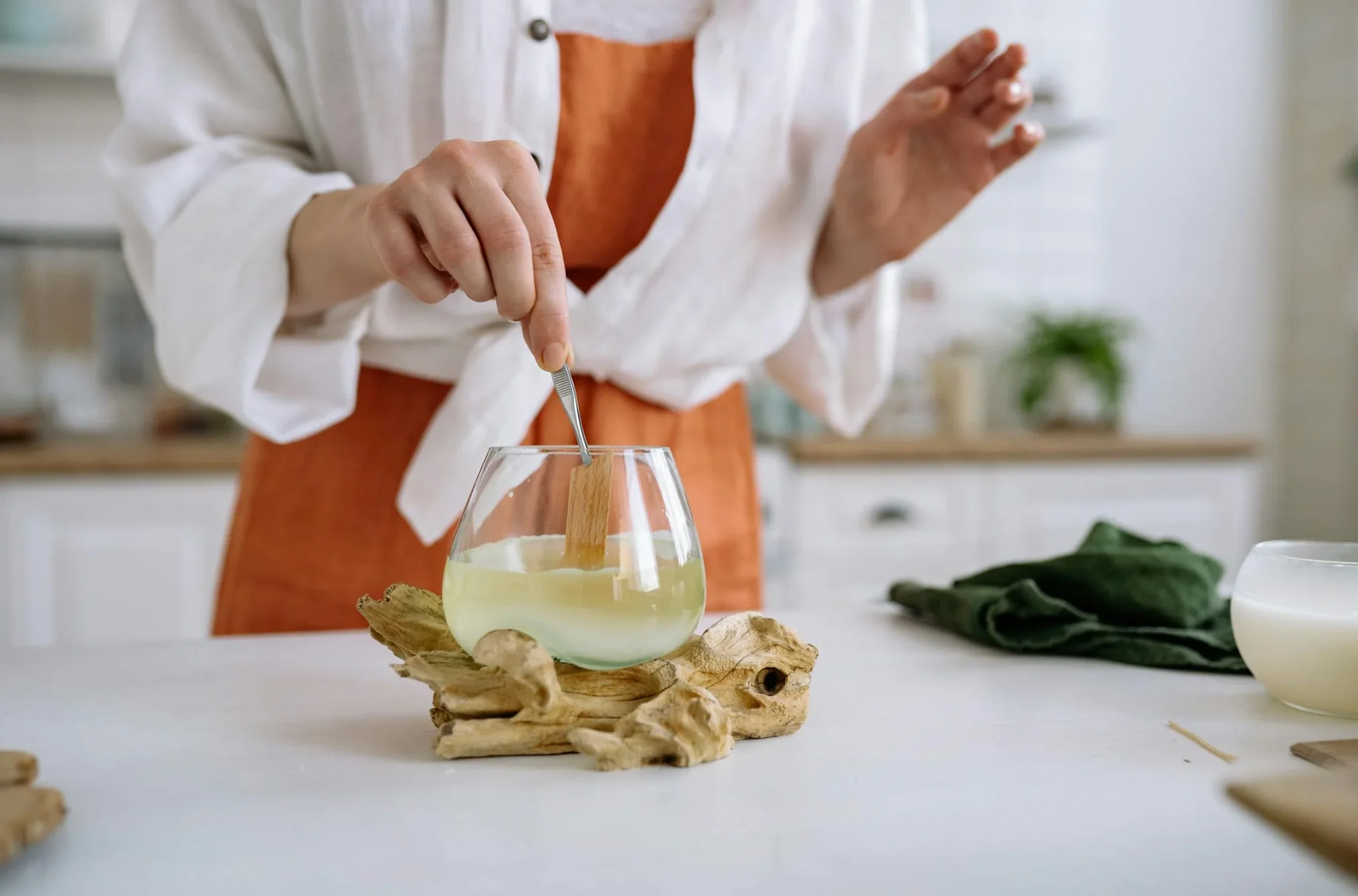 Personne mélangeant de la cire fondue dans un verre pour fabriquer une bougie artisanale à Lyon.