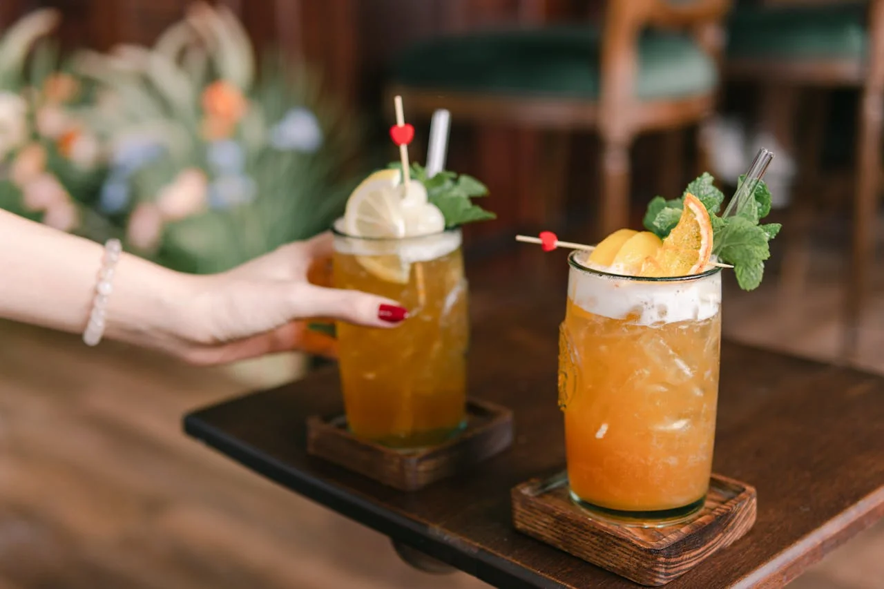 Deux verres de cocktails garnis de fruits et de menthe sur une table en bois dans un atelier à Paris.