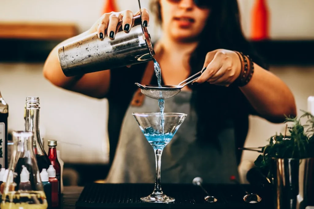 Mixologue versant un cocktail bleu dans un verre martini lors d’un atelier à Paris.