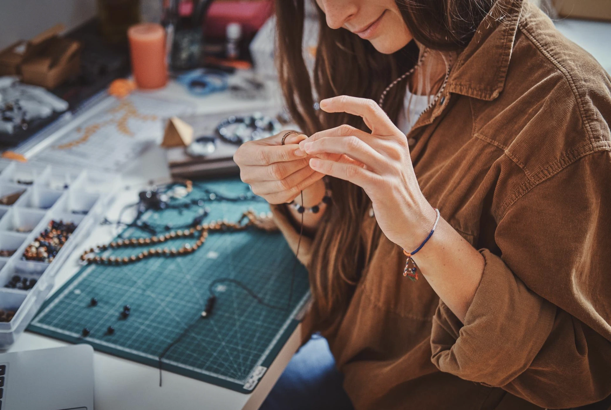 Groupe de femmes concentrées, manipulant perles et fils pour créer des bijoux personnalisés lors d’un atelier EVJF.