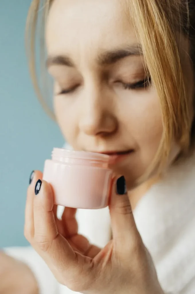 Femme fermant les yeux en sentant un pot de cosmétique lors d’un atelier création à Lyon.