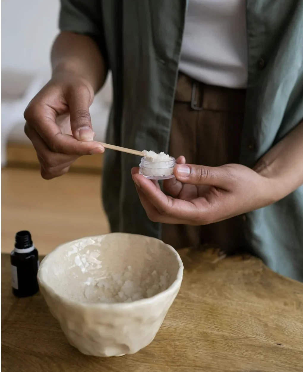 Mains remplissant un petit pot de baume naturel lors d’un atelier création cosmétique à Lyon.