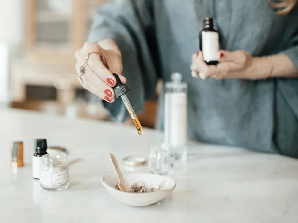 Femme versant des gouttes d’huile essentielle dans un bol lors d’un atelier création cosmétique à Lyon.