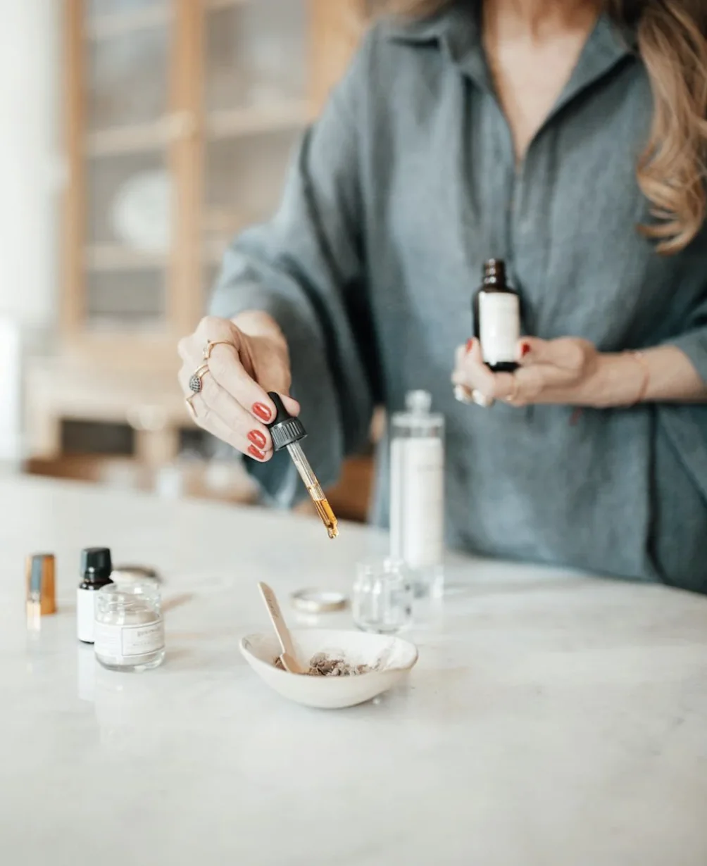 Femme versant des gouttes d’huile essentielle dans un bol lors d’un atelier création cosmétique à Lyon.