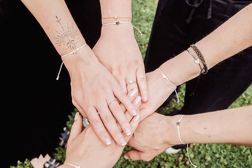 Mains d’amies portant des bracelets assortis posées ensemble lors d’un atelier DIY EVJF à Cabourg