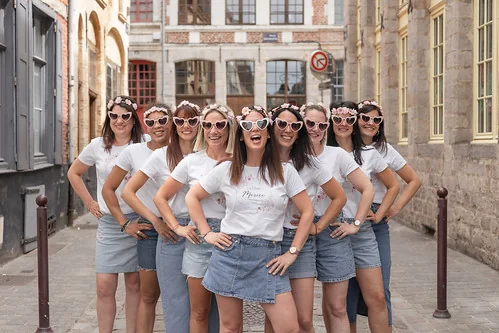 Groupe d’amies en jupes et shorts en jean avec t-shirts blancs et lunettes cœur posant en ville lors d’un atelier DIY EVJF à Cabourg