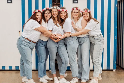 Amies en jeans et t-shirts blancs avec couronnes de fleurs posant ensemble lors d’un atelier DIY EVJF à Cabourg