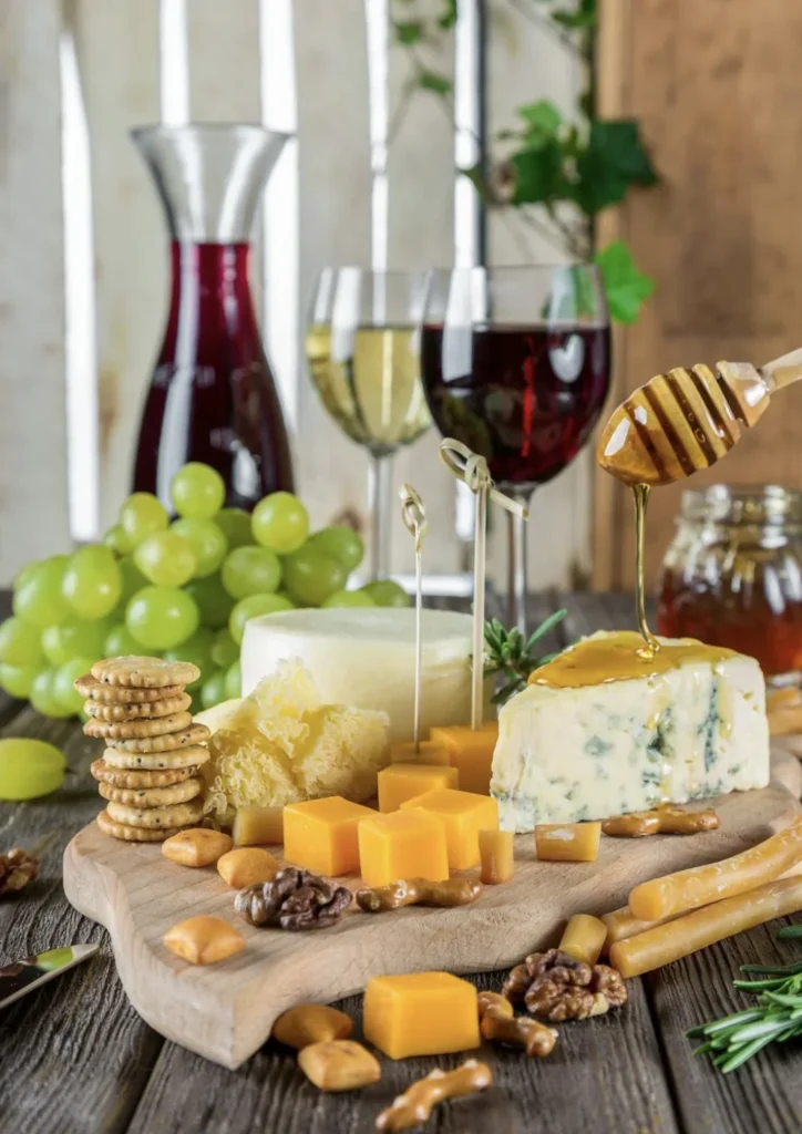 Plateau de fromages, miel et crackers avec verres de vin rouge et blanc lors d’un atelier gourmand à Lyon.