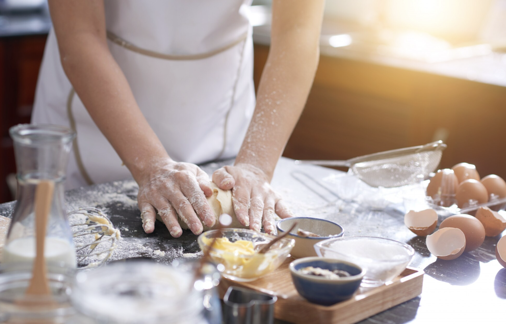 Femme seule en train de pétrir la pâte à pâtisserie sur un plan de travail, concentrée et souriante lors d’un atelier EVJF.