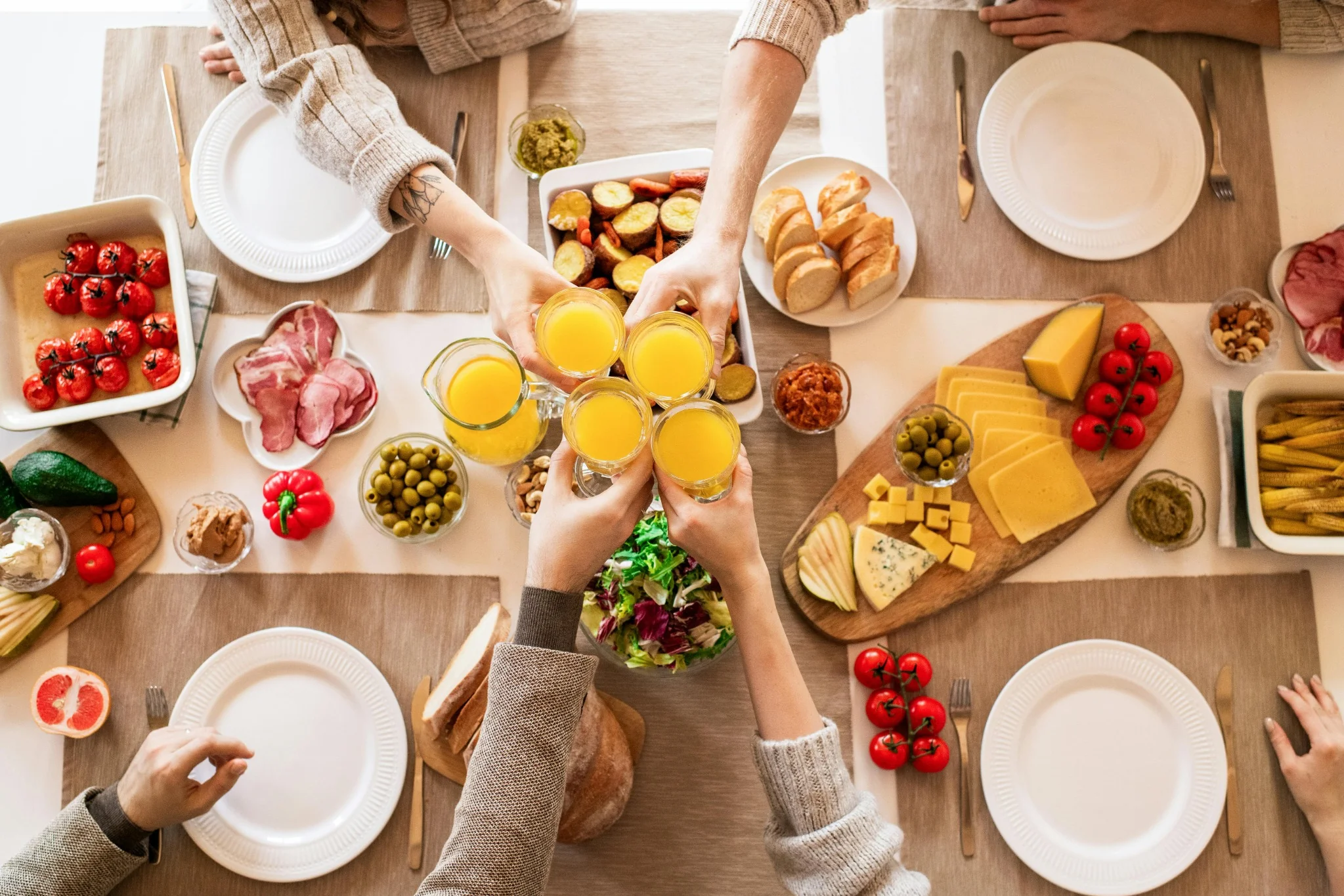 Vue aérienne d’un brunch convivial à Lille avec fromages, charcuterie, légumes et verres de jus d’orange portés en toast
