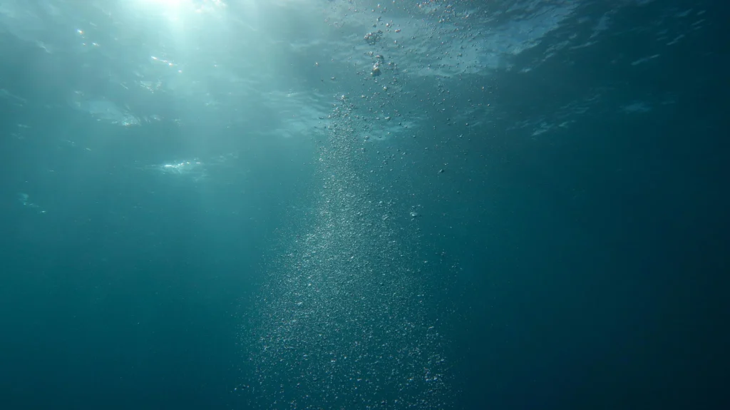 Colonnes de bulles remontant dans une eau turquoise éclairée par la lumière naturelle en mer Méditerranée