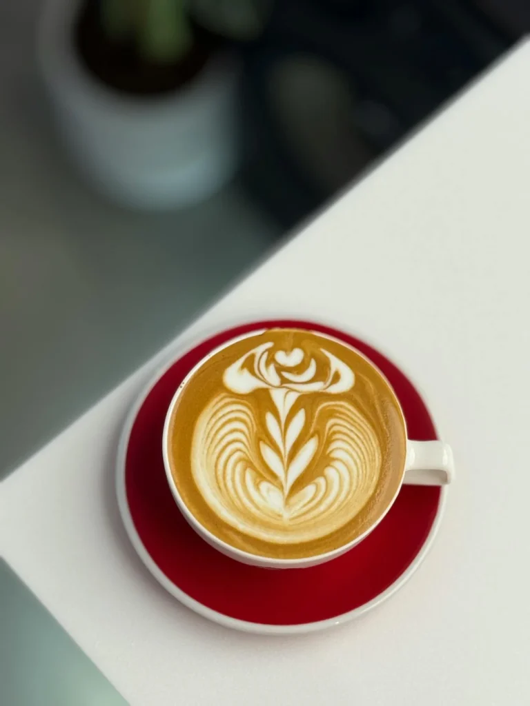 Tasse de café latte avec motif latte art en forme de fleur, servie lors d’un brunch EVJF à Paris