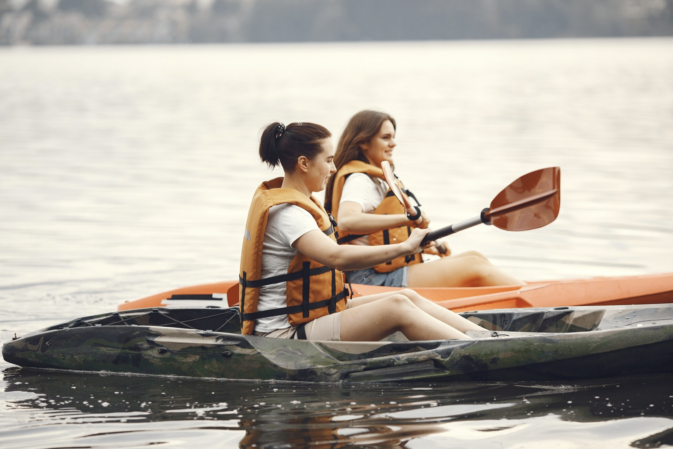 Deux participantes EVJF à Bordeaux en train de faire du kayak, pagayant sur l’eau dans un cadre naturel et paisible