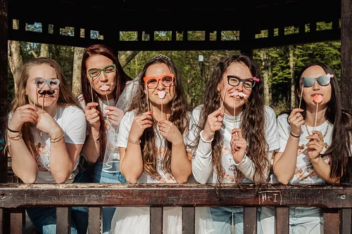 Cinq femmes souriantes tenant des accessoires photo amusants