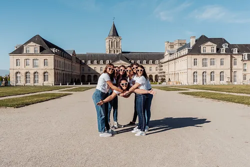 groupe de femmes en jean et t shirt blanc pose en cercle devant un monument historique a cabourg pendant un evjf