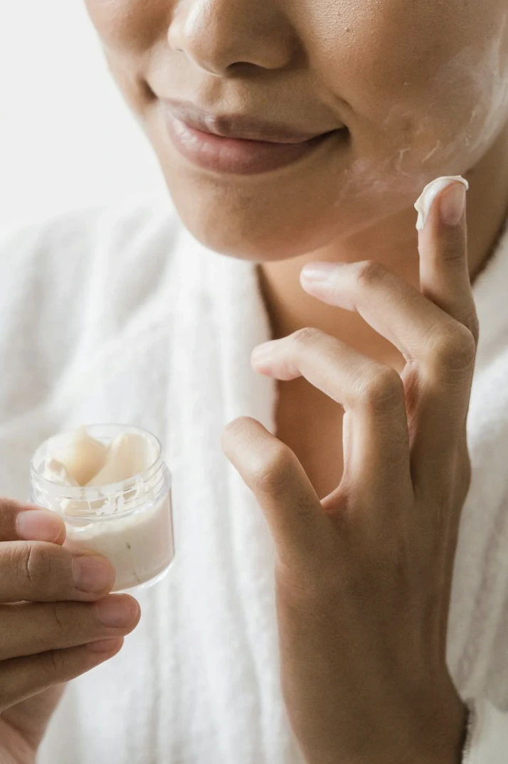Femme appliquant une crème cosmétique naturelle sur sa peau lors d’un atelier.