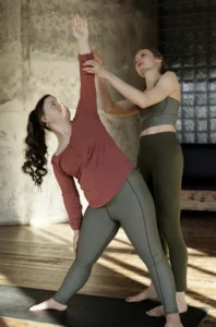Une professeure de yoga aidant une élève à ajuster sa posture dans une salle lumineuse à Bordeaux