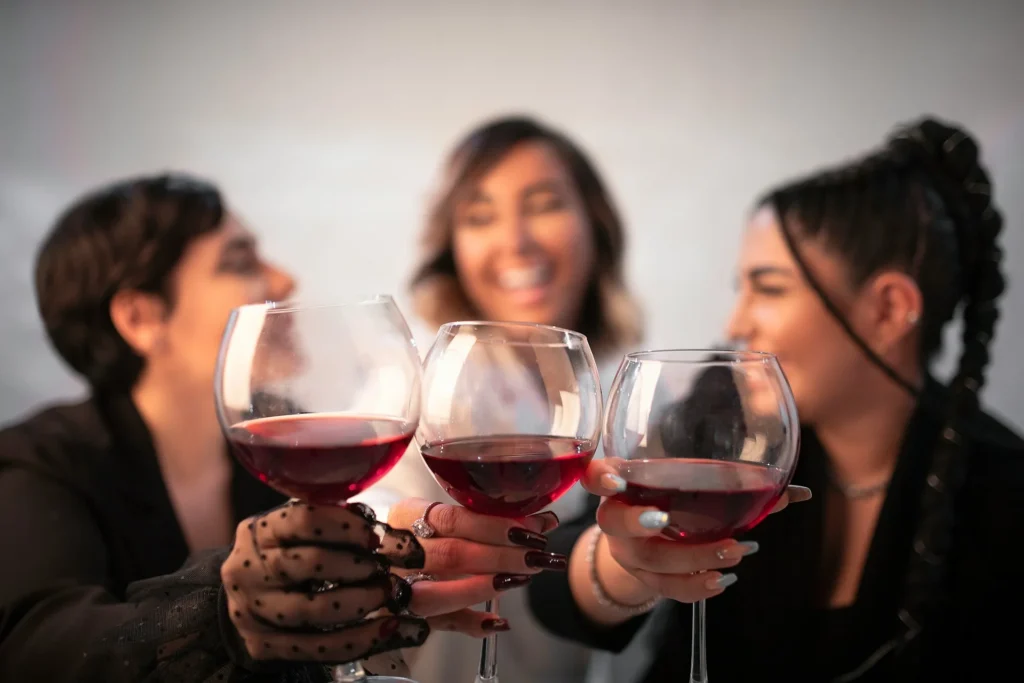 Trois amies riant et trinquant avec des verres de vin rouge lors d'un moment convivial